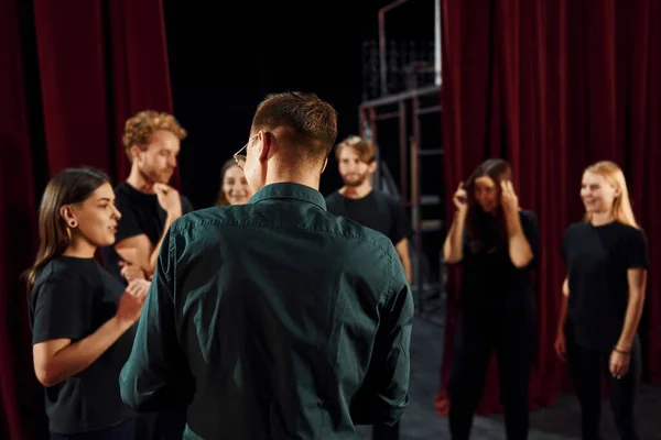 Working together. Group of actors in dark colored clothes on rehearsal in the theater.