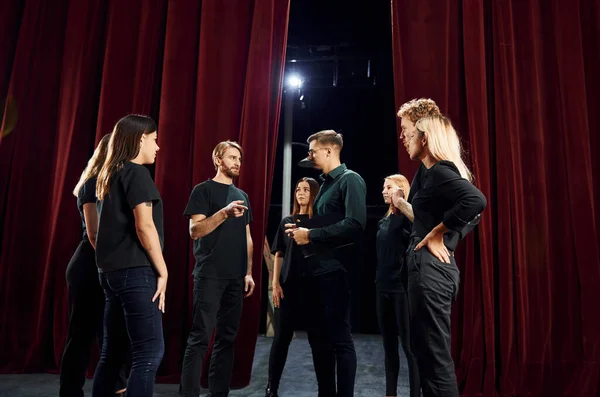 Group of actors in dark colored clothes on rehearsal in the theater.