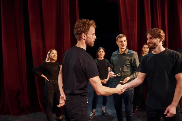 Eye contact practice. Group of actors in dark colored clothes on rehearsal in the theater.