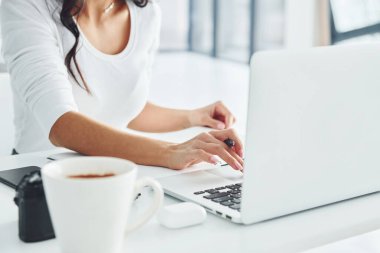 Dizüstü bilgisayar ve not defteri kullanarak. Gündüz vakti ofiste çalışan serbest çalışan genç bir bayan..