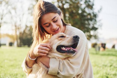 Evcil hayvanı kucaklamak. Genç bayan Golden Retriever ile parkta yürüyüş yapıyor..