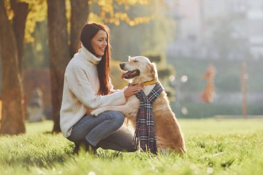 Eşarp takıyordu. Genç bayan Golden Retriever ile parkta yürüyüş yapıyor..