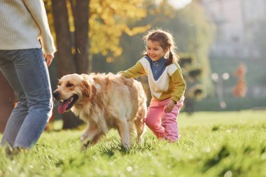 Anne ve kızı parkta Golden Retriever köpeğiyle yürüyüşe çıktılar..