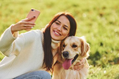 Selfie yapıyorum. Genç bayan Golden Retriever ile parkta yürüyüş yapıyor..
