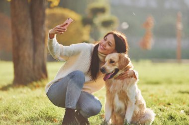 Selfie yapıyorum. Genç bayan Golden Retriever ile parkta yürüyüş yapıyor..