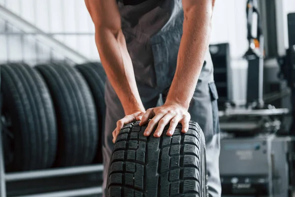 Rullar Däcket Vuxen Man Grå Uniform Arbetar Bilsalongen — Stockfoto