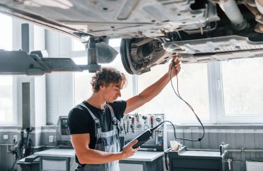 Özellikleri test etmek için özel bir araç. Gri üniformalı yetişkin adam otomobil salonunda çalışıyor..