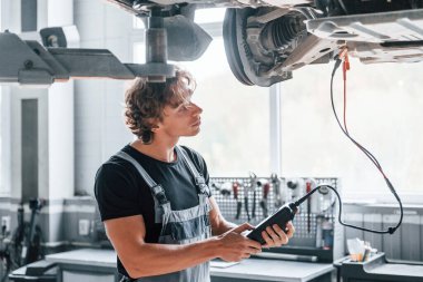 Özellikleri test etmek için özel bir araç. Gri üniformalı yetişkin adam otomobil salonunda çalışıyor..