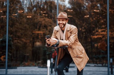 Elektrikli scooter kullanıyorum. Şık giyimli genç erkek manken gündüz vakti şehir dışında..