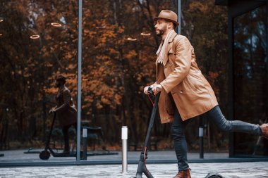 Elektrikli scooter kullanıyorum. Şık giyimli genç erkek manken gündüz vakti şehir dışında..