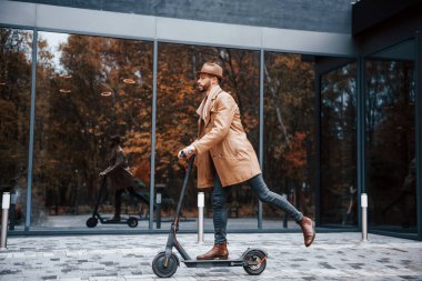 Elektrikli scooter kullanıyorum. Şık giyimli genç erkek manken gündüz vakti şehir dışında..