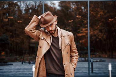 Cam kapılı binaya karşı durmak. Şık giyimli genç erkek manken gündüz vakti şehir dışında..