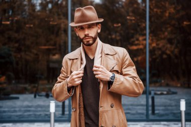 Cam kapılı binaya karşı durmak. Şık giyimli genç erkek manken gündüz vakti şehir dışında..