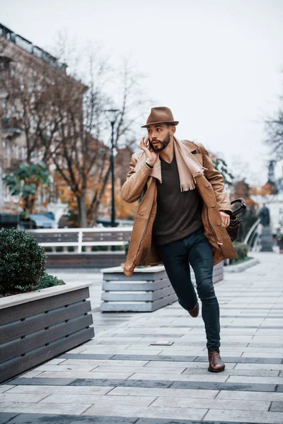 Running, late for meeting. Young male model in fashionable clothes is outdoors in the city at daytime.