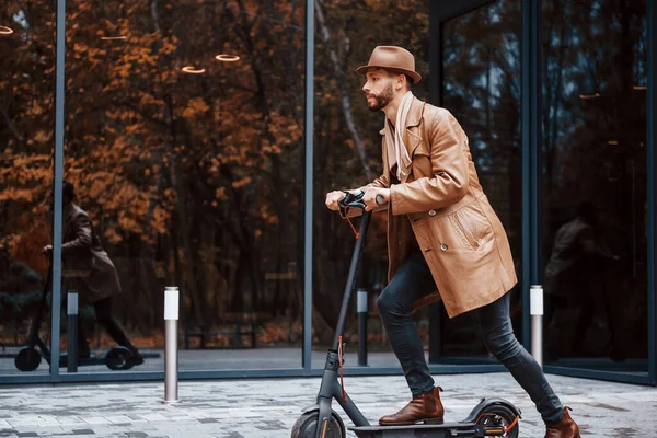 Elektrikli scooter kullanıyorum. Şık giyimli genç erkek manken gündüz vakti şehir dışında..