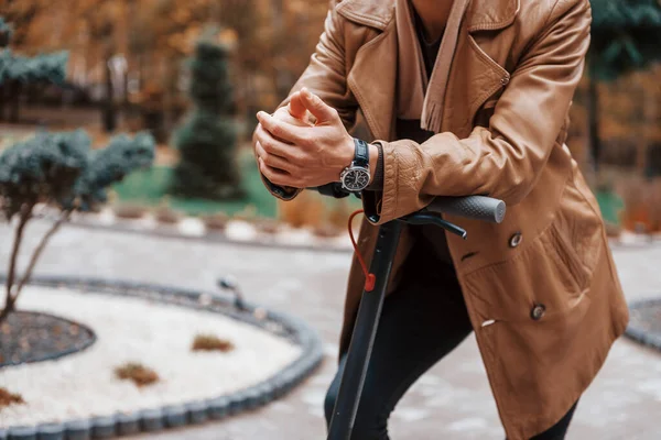 Young male model in fashionable clothes is outdoors in the park at daytime.