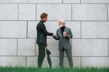 Şemsiye ve bir bardak içki. Zarif giyinmiş son sınıf öğrencisi olan genç adam açık havada birlikte. İş kavramı.