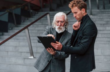 Okuma planı. Zarif giyinmiş son sınıf öğrencisi olan genç adam açık havada birlikte. İş kavramı.