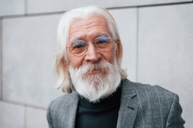 Açık havada duran gri saçlı ve sakallı kıdemli iş adamının portresi.