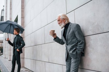 Zarif giyinmiş son sınıf öğrencisi olan genç adam açık havada birlikte. İş kavramı.