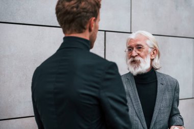 Buluşma var. Zarif giyinmiş son sınıf öğrencisi olan genç adam açık havada birlikte. İş kavramı.