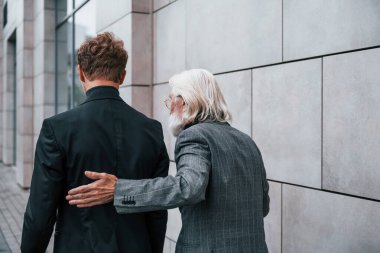 Buluşma var. Zarif giyinmiş son sınıf öğrencisi olan genç adam açık havada birlikte. İş kavramı.