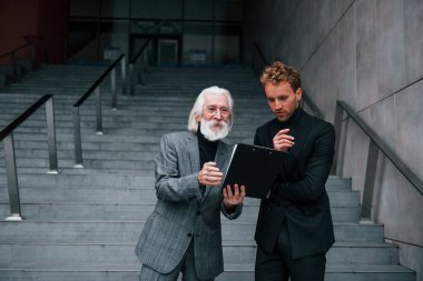 Not defterini tutuyorum. Zarif giyinmiş son sınıf öğrencisi olan genç adam açık havada birlikte. İş kavramı.