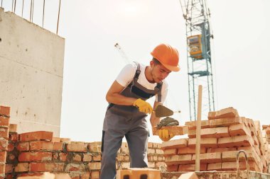 Üniformalı genç inşaat işçisi tamamlanmamış binada meşgul..