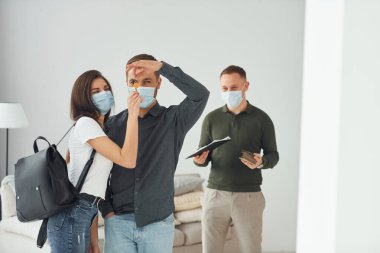 Adam genç çifte daire seçmede yardım ediyor. Maskeli..