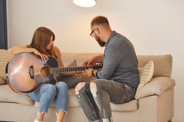 Gitar öğretmeni enstrümanı genç bir kadına nasıl çalacağını gösteriyor..