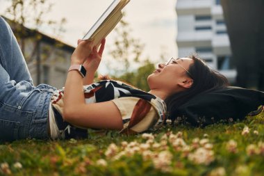 Çimlerin üzerinde yatıyordu. Genç Asyalı kadın gündüz vakti dışarıda..