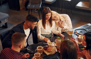 Kadınlar ve erkekler. Bir grup genç arkadaş barda birlikte oturup bira içiyorlar..