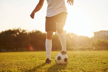 Güzel güneş ışığı. Genç futbolcu spor sahasında antrenman yapıyor..