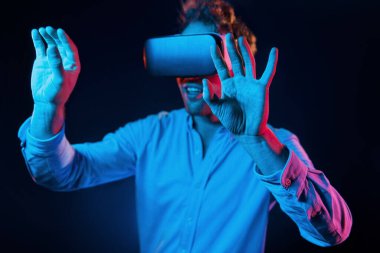 Sanal gözlük oyun deneyimi. Neon ışıkları. Genç Avrupalı adam karanlık stüdyoda..