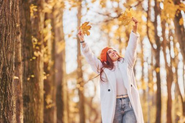 Ön manzara. Beyaz önlüklü kadın sonbahar parkında eğleniyor..