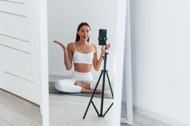 Telefon video kaydediyor. İnce vücutlu beyaz kadın gündüz vakti evdedir..
