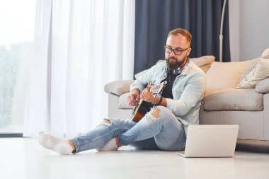 Yaratıcı uğraş. Gündelik giysiler içinde ve akustik gitarlı bir adam içeride..