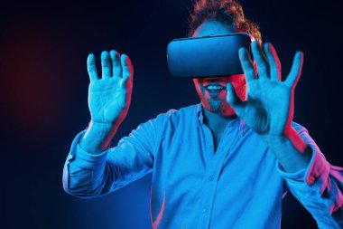 Sanal gözlük oyun deneyimi. Neon ışıkları. Genç Avrupalı adam karanlık stüdyoda..