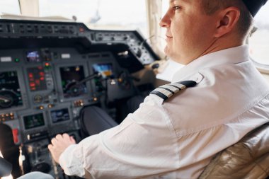 Sakin atmosfer. Resmi kıyafetli pilot kokpitte oturur ve uçağı kontrol eder..
