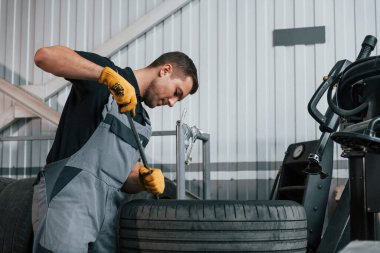 Kırık tekerlekle çalışmak. Üniformalı adam otomobil servisinde çalışıyor..