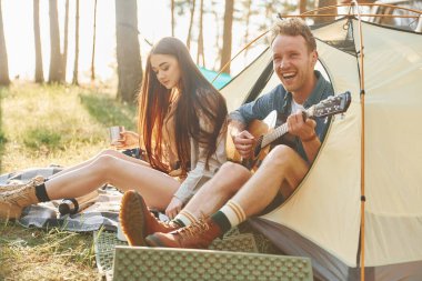 Gitar çalan adam. Genç çift gündüz vakti ormanda geziyor..