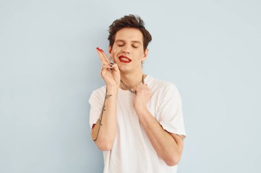 Genç eşcinsel adam stüdyoda duruyor ve kameraya poz veriyor. Hareketleri gösterir.