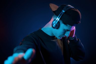 Adam kulaklık kullanıyor. Neon ışıkları. Genç Avrupalı adam karanlık stüdyoda..