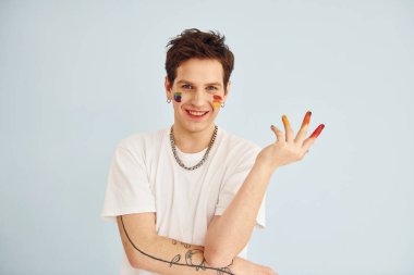 Genç eşcinsel adam stüdyoda duruyor ve kameraya poz veriyor. Hareketleri gösterir.