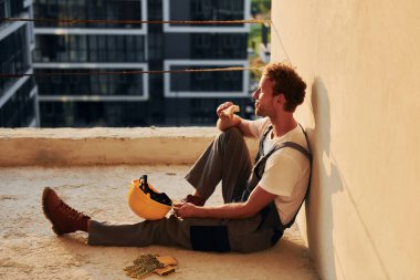 Yerde oturuyordum. Gündüz vakti inşaatta üniformalı genç bir adam çalışıyor..