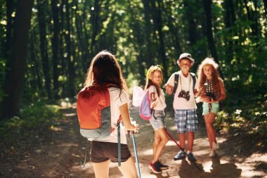 Maceraya hazırım. Çocuklar seyahat ekipmanlarıyla ormanda geziniyorlar..