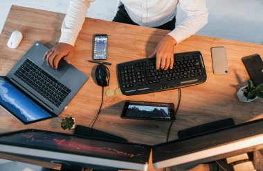 Manzarayı kapat. Resmi giyinmiş genç işadamı birden fazla ekranla ofiste..