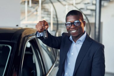 Arabanın yanında duruyor. Siyah takım elbiseli genç Afro-Amerikan iş adamı Ototalon..