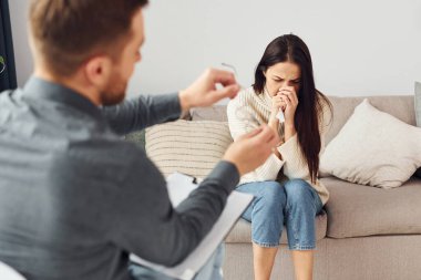 Genç bir kadın bir psikologda resepsiyonda. Kanepede oturuyor..