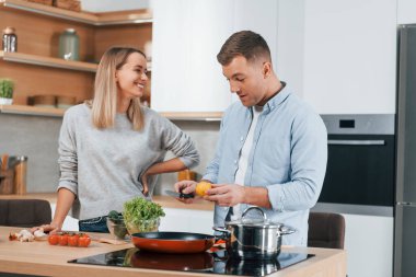 Birbirleriyle konuşuyorlar. Modern mutfakta yemek hazırlayan bir çift..